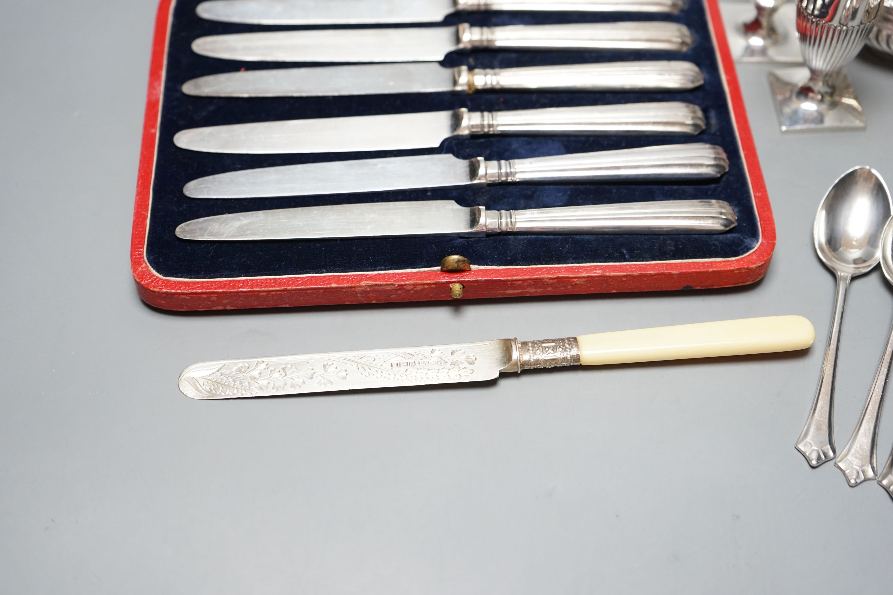 A pair of Victorian silver pepperettes, a pair of later silver salts, six silver teaspoons, a silver dessert knife and a cased set of silver handled tea knives.